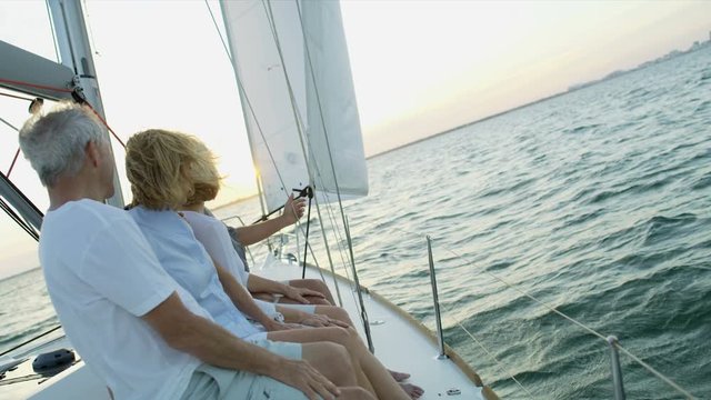 Mature American male and female friends outdoors on their sailing boat at sunrise enjoying their vacation and retirement living  