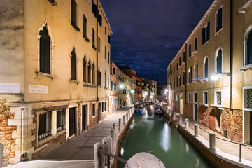 A narrow canal - street Fondamente Di Borgo with boats in Venice at night, Italy.