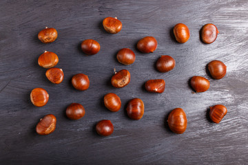 Fototapeta na wymiar pile of sweet chestnuts on black wooden background