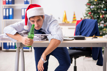 Young handsome employee celebrating Christmas at workplace 