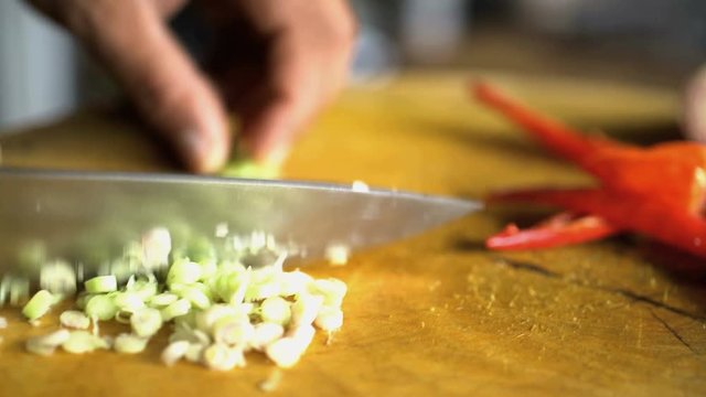 Cutting a selection of healthy nutritious vegetables on wooden chopping board with Balinese Blakas in Indonesia