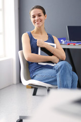 Young woman sitting at the desk with instruments, plan and laptop.