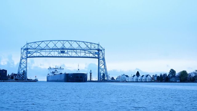 Iron Ore Ship arrives under Duluth Minnesota aerial lift bridge from Lake Superior on cloudy morning.