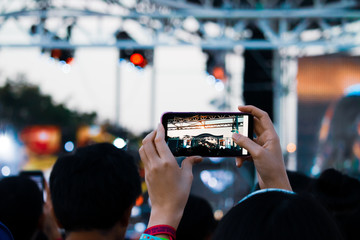 Hand with a smartphone records live music festival, Taking photo of concert stage, live concert, music festival