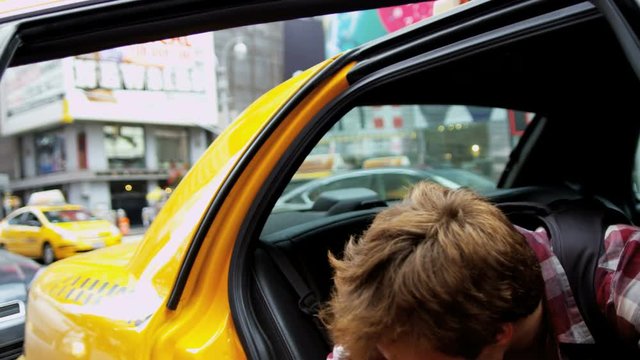 Young male Caucasian tourist achieving his ambitions arriving yellow cab Times Square Manhattan 