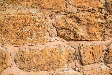 Fototapeta premium Old beige stone wall background texture close up