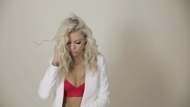 Sexy blonde female model posing wearing a red bra and white jacket as her hair blows with copy space