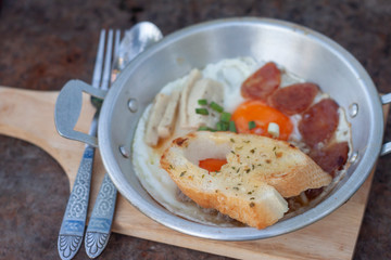 Closeup bread in pan-fried egg with toppings is breakfast in Thai style. 