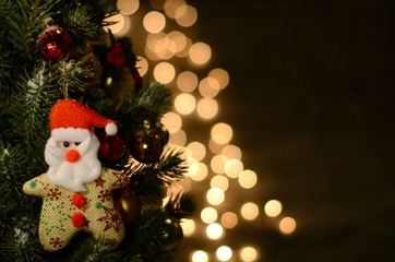 Santa Claus ornament on Christmas tree with snow and bokeh light as background for Christmas holiday.