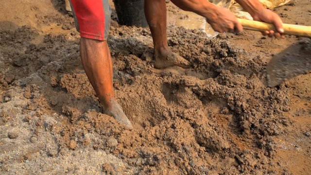 Male treading soil material to make handmade bricks Java Indonesia