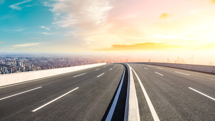 Panoramic city skyline and buildings with empty asphalt road at sunset