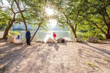 View of tourist walking on the bridge cross reservoir with mountain and blue sky background, Khao Ngu Stone Park, Ratchaburi, Thailand