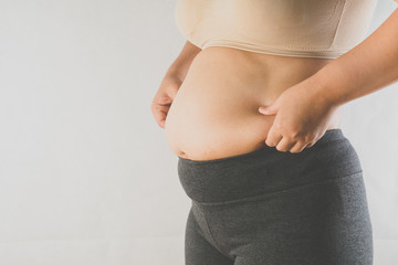 woman's hand holding excessive belly fat