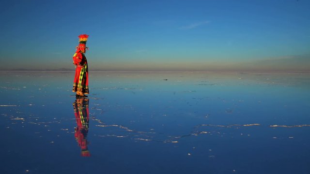 Traditional National dress worn by Bolivian woman standing on the Salar de Uyuni Salt flats at sunrise South America 