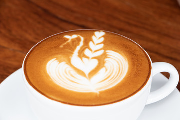 coffee cup latte art on wooden table.hot drink coffee with milk froth for breakfast.heart shape art foam texture top view.