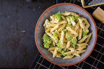 Penne pasta with cabbage romanesco on black table. Vegetarian food. Italian menu. Top view. Flat lay