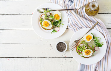 Healthy food. Breakfast. Avocado egg sandwich with whole grain bread on white wooden background. Top view. Flat lay