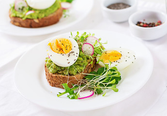 Healthy food. Breakfast. Avocado egg sandwich with whole grain bread on white wooden background.
