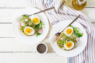 Healthy food. Breakfast. Avocado egg sandwich with whole grain bread on white wooden background. Top view. Flat lay