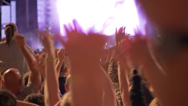 Wide shot of concert through hands waving in air