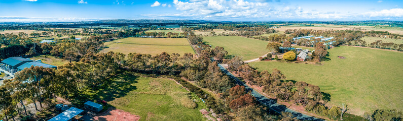 Fototapeta na wymiar Aerial panorama of road, meadows and pastures on bright summer day in Australia
