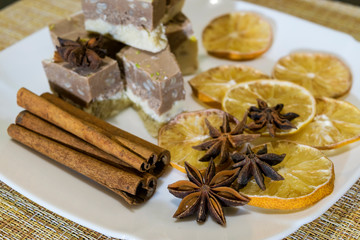 Lie on a plate of cakes, a lemon slices with star anise and cinnamon sticks.