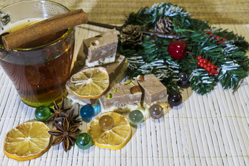Hot drink among the holiday decorations. The table is decorated with cinnamon sticks, star anise, cake, lemon slices, pine branch.