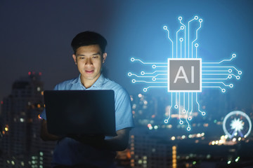 Businessman stand on roof top using laptop with hold the (AI)Artificial intelligence hologram,smart city and network connect concept