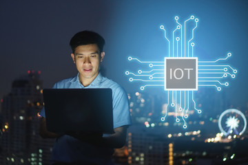 Businessman stand on roof top using laptop with IOT, internet of things,smart city and network connect concept