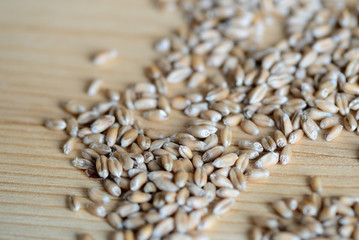 Obraz premium Scattered wheat grains on wooden background close up
