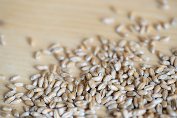Obraz premium Scattered wheat grains on wooden background close up