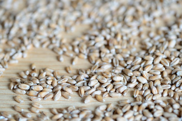 Obraz premium Scattered wheat grains on wooden background close up