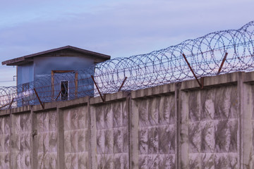 The guarding tower and the fence with the barbed wire of the prison or the closed area 