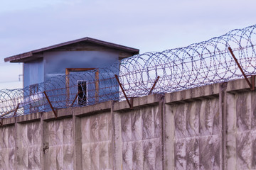 The guarding tower and the fence with the barbed wire of the prison or the closed area 