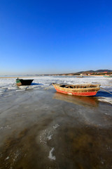 fishing boats, ice and snow by the sea