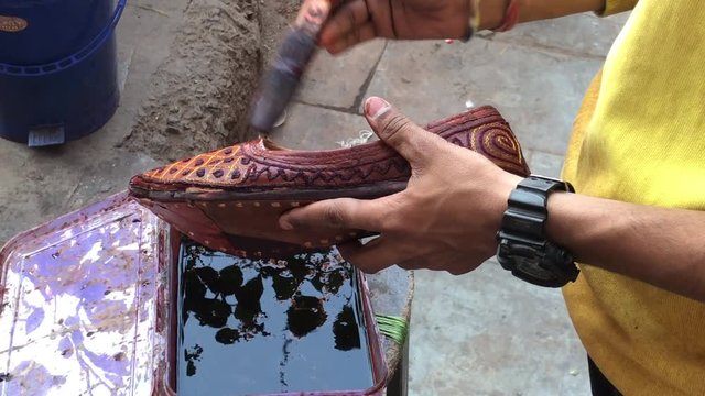 A local vendor shoe seller at day at his own shop polishing the Indian chappals at Jaipur