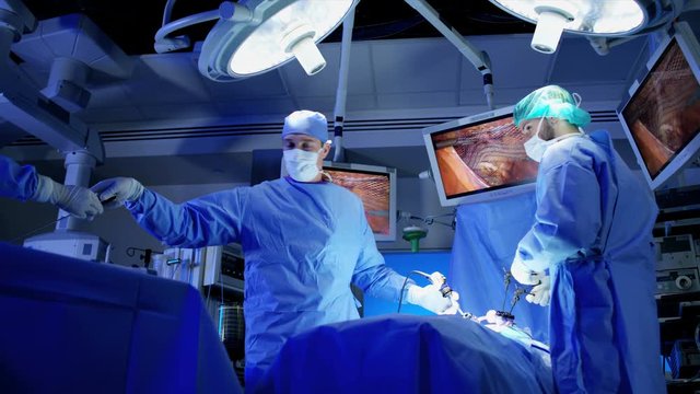 Caucasian surgical male team in scrubs in the operating theater of European origin using an Endoscopy to specialise in Laparoscopy surgery via camera technology 