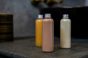 Spa cosmetics in plastic bottles on dark gray concrete table, bathroom interior. Beauty blogger, salon therapy, branding mockup, package, minimalism concept