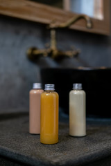 Spa cosmetics in plastic bottles on dark gray concrete table, bathroom interior. Beauty blogger, salon therapy, branding mockup, package, minimalism concept