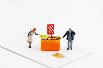 Miniatrue people: Shoppers buy goods on sale with discount tray on credit cart. Tourism, shopping or business concept.