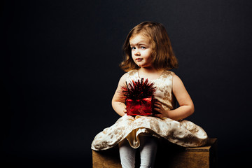 Portrait of a lovely little girl with red gift, isolated on black studio background