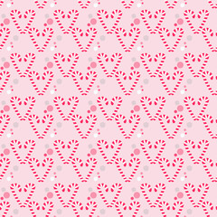 Christmas seamless pattern with candy canes in shape of heart and color circles on pink background. Background for wrapping paper, fabric print, greeting cards design.