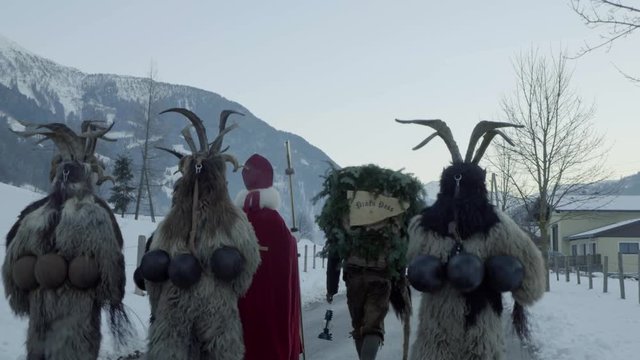 A group of Traditional Krampus from behind run in Gastein Austria. Folklore during christmas in Salzburg. Mountain village demons with masks and horn during advent. Saint Nicholas and his krampus.
