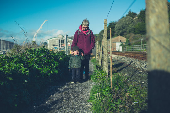 Toddler with grandmother walking by railway tracks