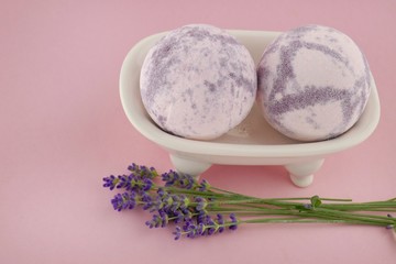 Lavender Bath Bombs.purple bath bombs and fresh lavender flowers in a ceramic bath on a  pink background.Pure organic body cosmetics with lavender extract