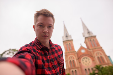 Tourist man taking selfie in front of Notre Dame Cathedral in Ho Chi Minh City