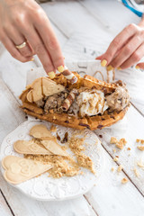 Closeup of woman holding waffles with ice-cream and cookies