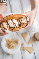 Closeup of woman holding waffles with ice-cream and cookies