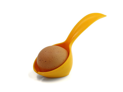 close up of egg and yellow spoon, holder isolated on white background