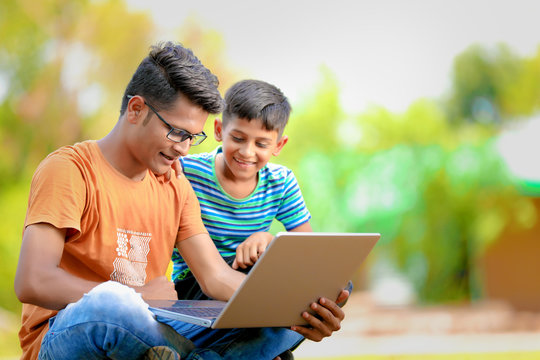 Two Indian Brothers Working On Laptop